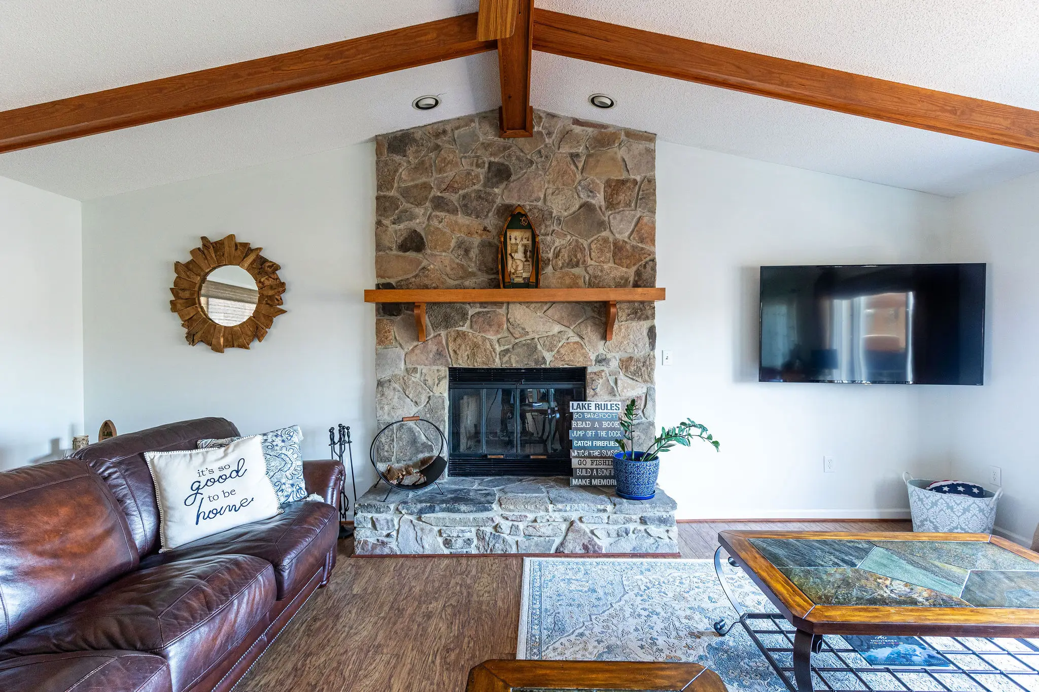 Living room with vaulted beams, stone fireplace and leather sofas